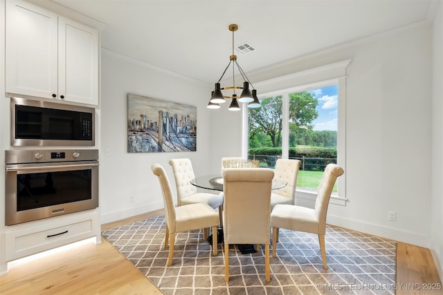 dining space with crown molding, a chandelier, light wood-style floors, and baseboards