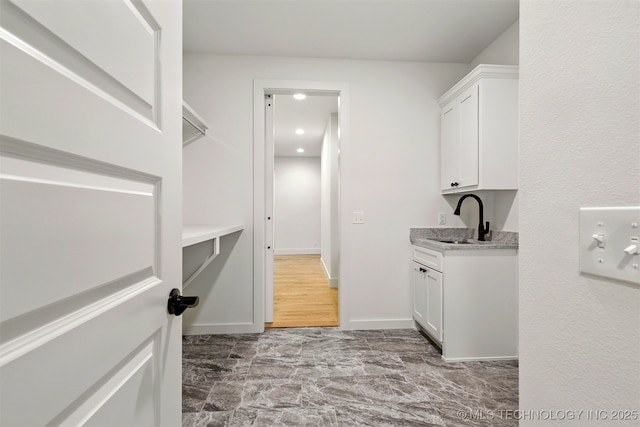 washroom with a sink, baseboards, and recessed lighting