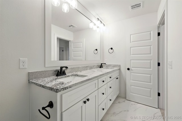 bathroom featuring marble finish flooring and double vanity