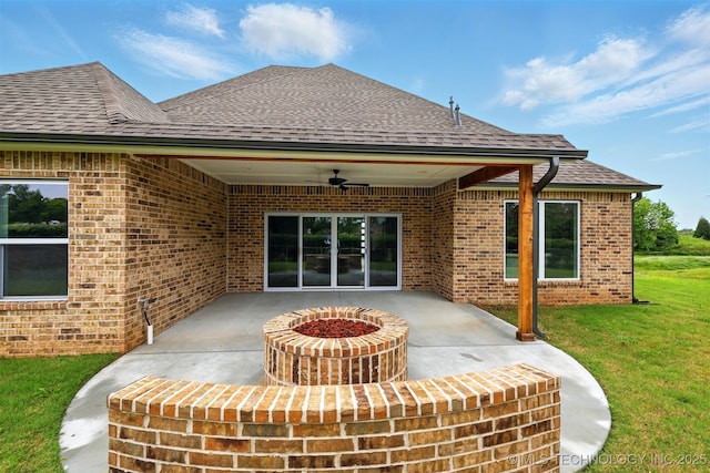 rear view of property with a ceiling fan, a patio, brick siding, and a fire pit