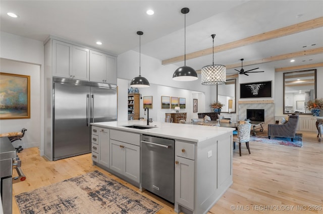 6038 E 119th Pl, Tulsa, OK 74137 - kitchen with appliances with stainless steel finishes, a ceiling fan, gray cabinets, a premium fireplace, and light wood finished floors