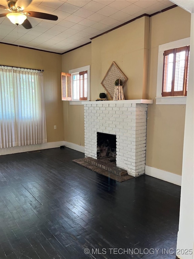 918 W Cedar St, Durant, OK 74701 - unfurnished living room featuring a ceiling fan, hardwood / wood-style floors, baseboards, a brick fireplace, and crown molding