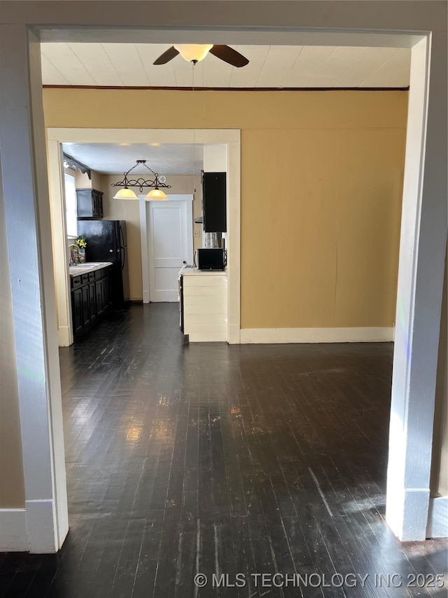 918 W Cedar St, Durant, OK 74701 - unfurnished living room featuring ceiling fan, baseboards, and dark wood-style flooring