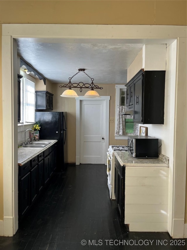 918 W Cedar St, Durant, OK 74701 - kitchen featuring a sink, stainless steel microwave, dark cabinetry, white gas range oven, and light countertops
