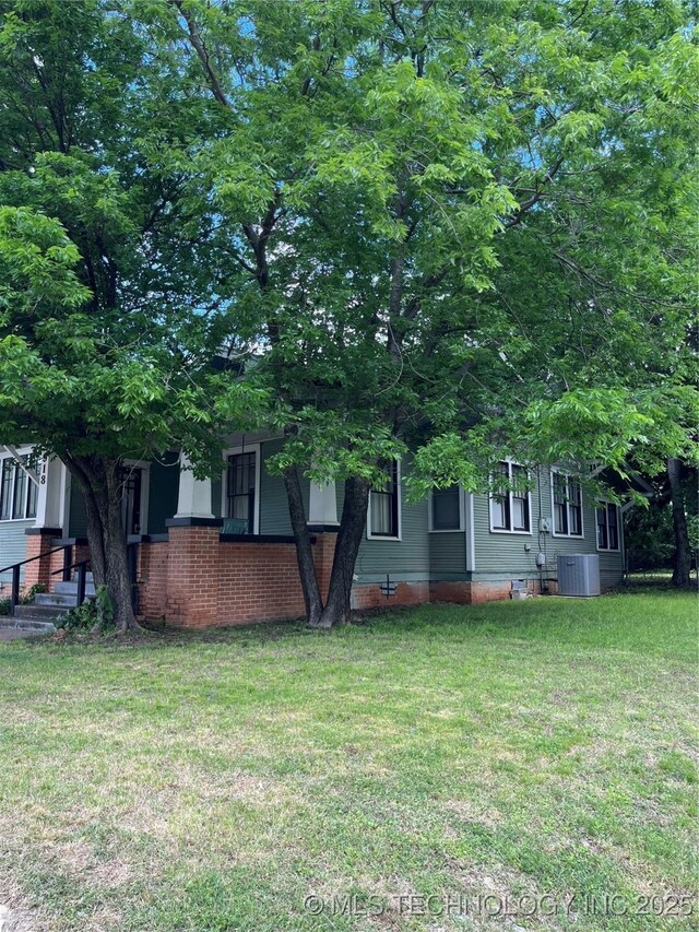 918 W Cedar St, Durant, OK 74701 - view of property hidden behind natural elements featuring central air condition unit and a front lawn