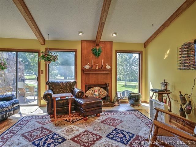 living room featuring beamed ceiling, a textured ceiling, and a fireplace