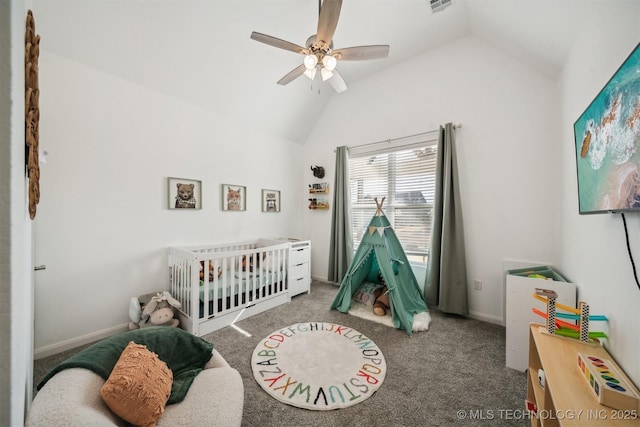 carpeted bedroom with vaulted ceiling, a crib, a ceiling fan, and baseboards