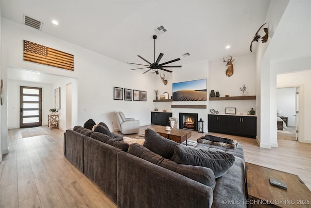 living room featuring light wood-style floors, ceiling fan, a glass covered fireplace, baseboards, and recessed lighting