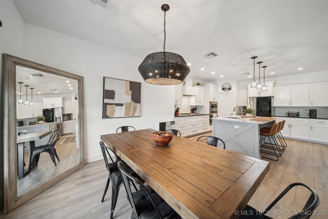 dining room with a chandelier, recessed lighting, and light wood-type flooring