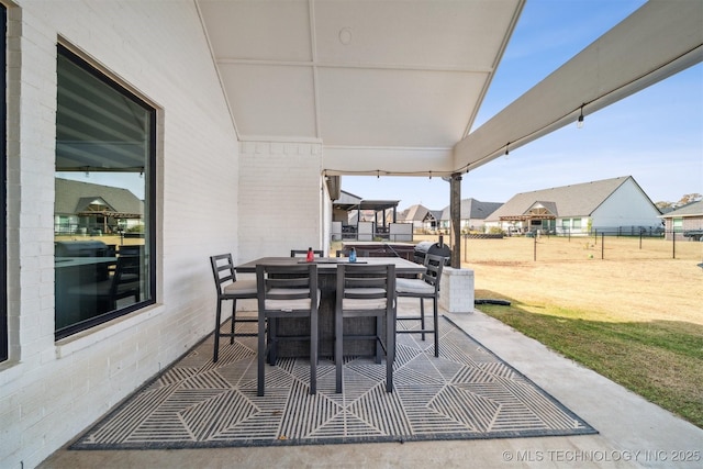 view of patio with outdoor dining area, fence, and a residential view