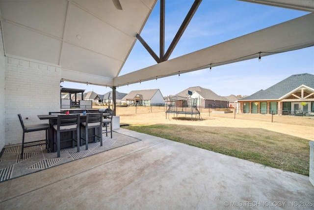 view of patio with a trampoline, outdoor dining area, and a residential view