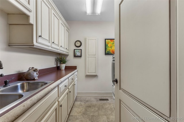 11616 S Hudson Ct, Tulsa, OK 74137 - laundry area featuring a sink, baseboards, and light stone finish floors
