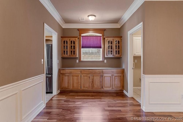 8531 S 70th E Ave, Tulsa, OK 74133 - bar area with freestanding refrigerator, wood finished floors, ornamental molding, wainscoting, and a decorative wall