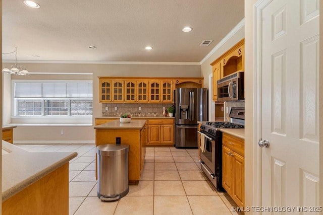 8531 S 70th E Ave, Tulsa, OK 74133 - kitchen with stainless steel appliances, ornamental molding, a kitchen island, light countertops, and light tile patterned flooring
