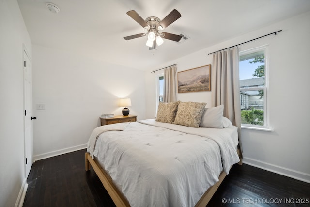 bedroom featuring multiple windows, baseboards, and dark wood-style flooring