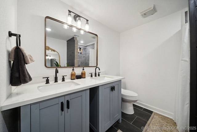 bathroom featuring toilet, a tile shower, tile patterned flooring, double vanity, and baseboards