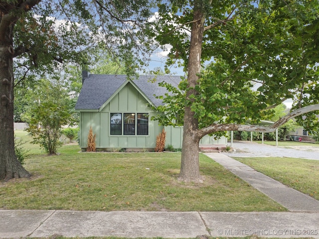 view of front of home with roof with shingles, board and batten siding, and a front lawn