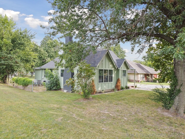view of side of property featuring board and batten siding, a lawn, a chimney, and a shingled roof