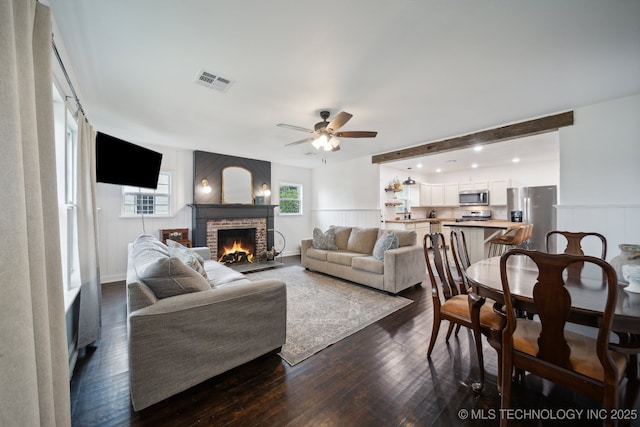 living area featuring a fireplace, dark wood-type flooring, and ceiling fan