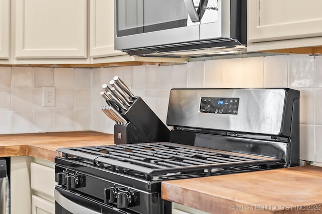 kitchen with appliances with stainless steel finishes, butcher block countertops, tasteful backsplash, and white cabinetry