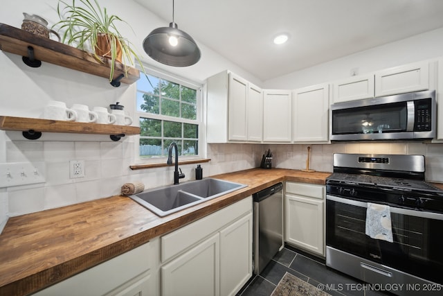 kitchen with stainless steel appliances, wooden counters, a sink, decorative backsplash, and recessed lighting