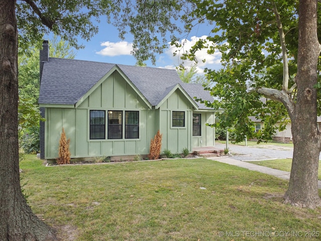 view of front of home with board and batten siding, a shingled roof, a chimney, and a front yard