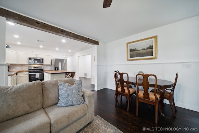 living room featuring dark wood-style flooring, beamed ceiling, baseboards, recessed lighting, and wainscoting