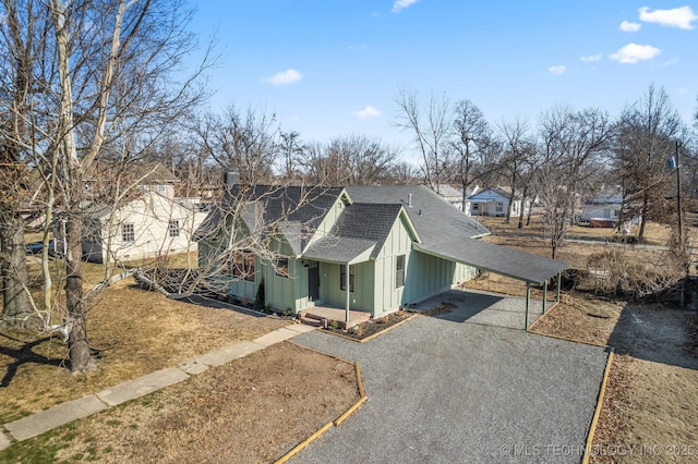 view of front of home featuring board and batten siding, a shingled roof, driveway, covered porch, and a carport