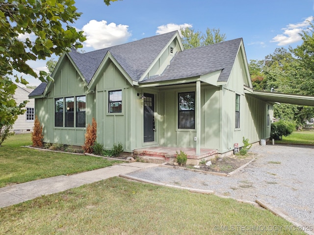 view of front of home featuring board and batten siding, a shingled roof, a front yard, and an attached carport