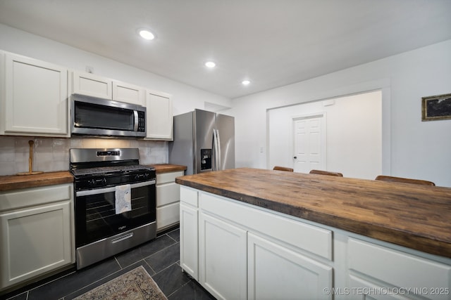 kitchen with butcher block countertops, stainless steel appliances, decorative backsplash, white cabinetry, and recessed lighting