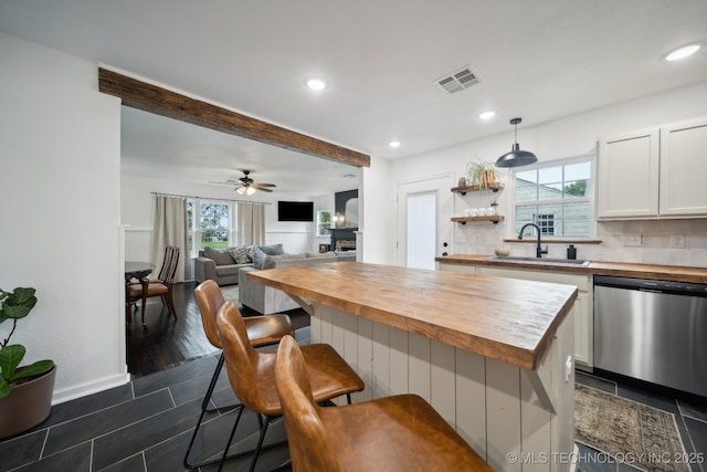 kitchen with wood counters, dishwasher, a sink, white cabinets, and recessed lighting