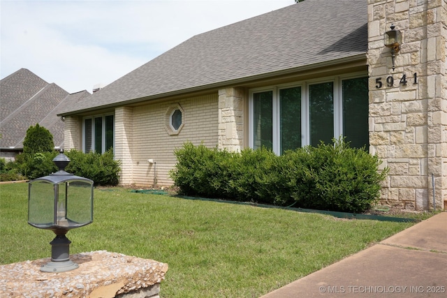 5941 E 87th St, Tulsa, OK 74133 - view of home's exterior featuring roof with shingles, a yard, and stone siding