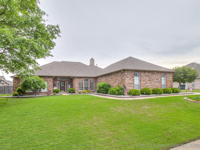 ranch-style house featuring brick siding, a chimney, a front lawn, and a shingled roof