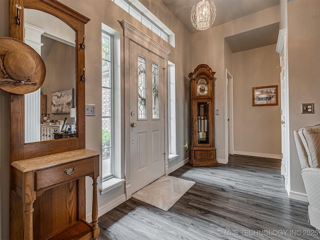 entrance foyer featuring dark wood finished floors, baseboards, and a chandelier