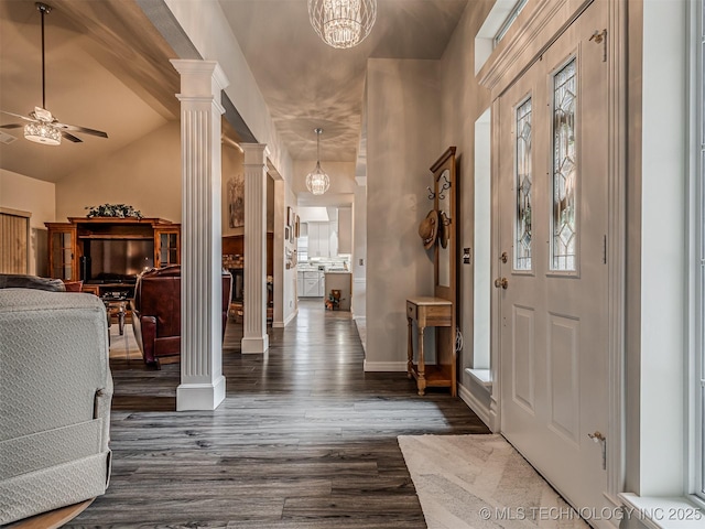 entrance foyer featuring ornate columns, ceiling fan, dark wood-type flooring, a chandelier, and baseboards