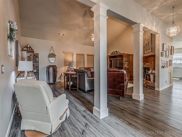 living room featuring decorative columns, wood finished floors, and baseboards