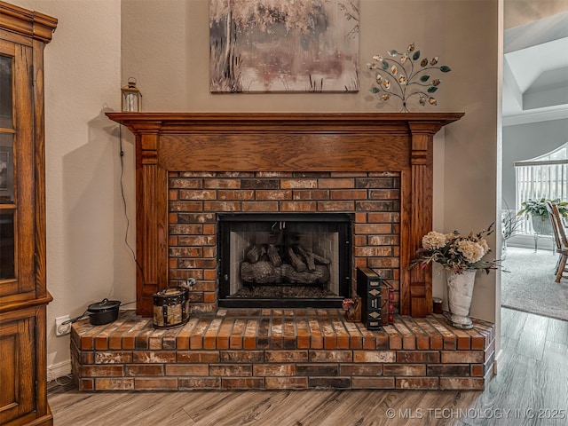 detailed view of wood finished floors, a fireplace, and baseboards
