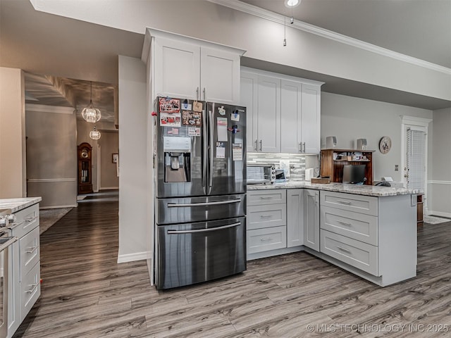 kitchen with stainless steel fridge, ornamental molding, a peninsula, light wood-type flooring, and tasteful backsplash
