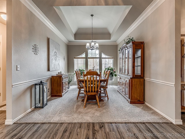 dining room featuring wood finished floors, a raised ceiling, baseboards, ornamental molding, and vaulted ceiling
