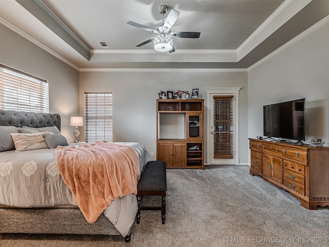 carpeted bedroom featuring a tray ceiling, ornamental molding, and ceiling fan