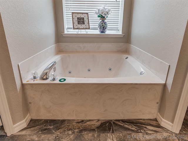 full bath featuring a textured wall, a whirlpool tub, and marble look tile flooring