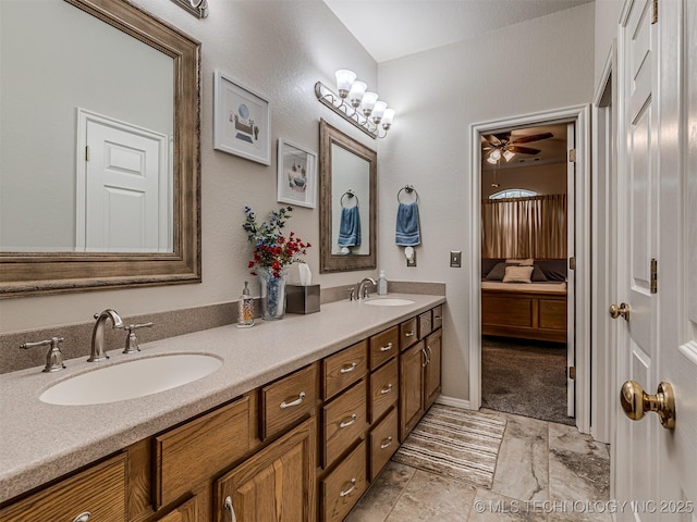 ensuite bathroom with double vanity, a ceiling fan, and marble look tile flooring
