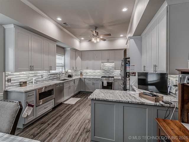 kitchen with gray cabinetry, stainless steel appliances, a sink, ceiling fan, and a peninsula