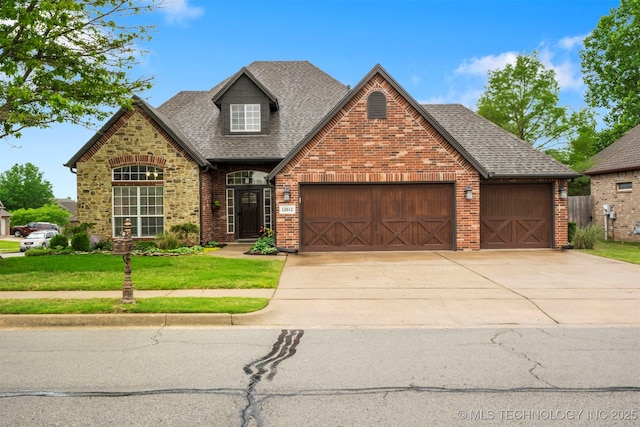 view of front facade featuring an attached garage, roof with shingles, driveway, brick siding, and a front yard