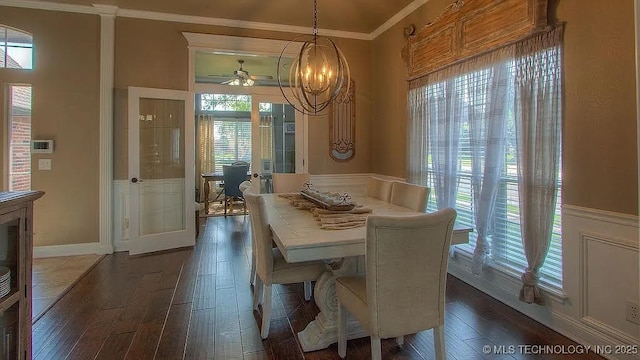 dining room with crown molding, dark wood finished floors, plenty of natural light, a wainscoted wall, and a ceiling fan