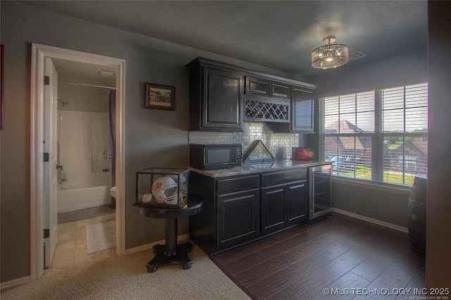 bar area with black microwave, baseboards, wine cooler, and decorative backsplash