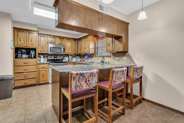 1205 Beaverly, Ardmore, OK 73401 - kitchen featuring appliances with stainless steel finishes, decorative backsplash, dark stone countertops, and a peninsula