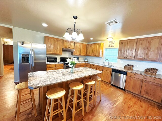 114537 Spring Creek Rd, Eufaula, OK 74432 - kitchen with stainless steel appliances, under cabinet range hood, light wood-style flooring, a kitchen breakfast bar, and recessed lighting
