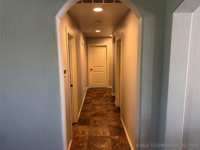 4715 Travertine, Ardmore, OK 73401 - hallway with baseboards, dark stone finish floors, arched walkways, and a textured wall