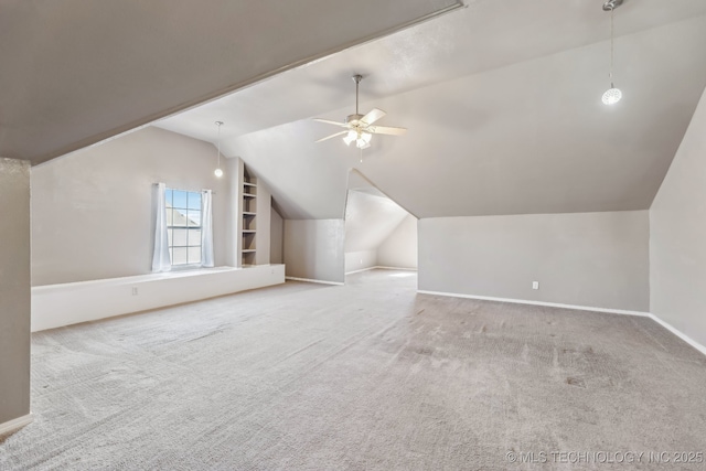 additional living space with vaulted ceiling, carpet flooring, baseboards, a ceiling fan, and built in features